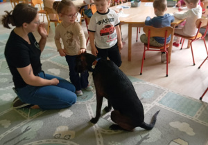 Dzieci siedzą obok psa