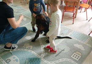 Dzieci siedzą obok brązowego psa