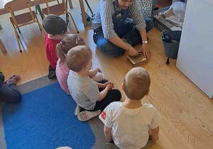 Dzieci uważnie przyglądają się jak przygotowuje się glinę