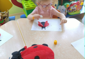 Dziewczynka wykonuje prace plastyczną - biedronke