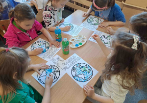 Dzieci wykonują pracę plastyczną przy użyciu farb i patyczków higienicznych tworząc obrazek ziemi