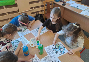 Dzieci wykonują pracę plastyczną przy użyciu farb i patyczków higienicznych tworząc obrazek ziemi