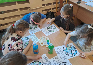 Dzieci wykonują pracę plastyczną przy użyciu farb i patyczków higienicznych tworząc obrazek ziemi