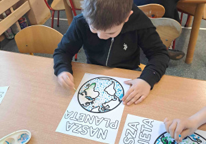 Dzieci wykonują pracę plastyczną przy użyciu farb i patyczków higienicznych tworząc obrazek ziemi