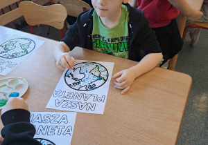 Dzieci wykonują pracę plastyczną przy użyciu farb i patyczków higienicznych tworząc obrazek ziemi