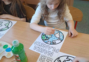 Dzieci wykonują pracę plastyczną przy użyciu farb i patyczków higienicznych tworząc obrazek ziemi