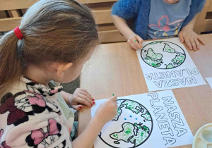 Dzieci wykonują pracę plastyczną przy użyciu farb i patyczków higienicznych tworząc obrazek ziemi