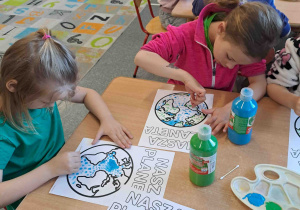 Dzieci wykonują pracę plastyczną przy użyciu farb i patyczków higienicznych tworząc obrazek ziemi