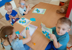 Dzieci naklejają kawałki papieru na kartkę