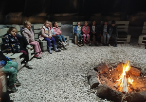 Dzieci siedzą przy ognisku