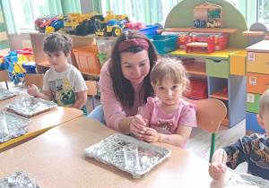 Dzieci wykonują eksperymenty przy stolikach