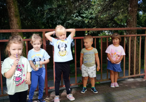 Dzieci stoją w rzędzie na tarasie.