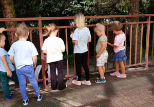 Dzieci rozmawiają z pracownikiem przedszkola.