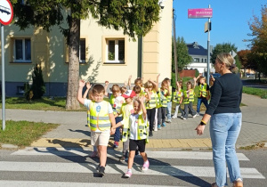 Dzieci przechodzą przez jezdnię w wyznaczonym miejscu pod opieką nauczyciela