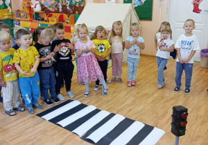 Grupa dzieci stoi przed wykonanym przez nauczycieli przejściem dla pieszych.