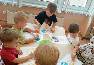 Chłopcy wyklejają plasteliną pracę plastyczną.