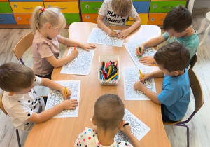 Dzieci przy stoliku kolorują.