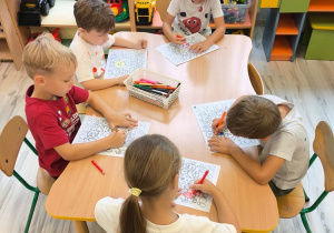 Dzieci przy stoliku kolorują.