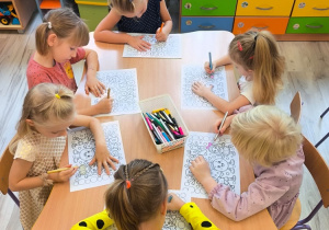 Dzieci przy stoliku kolorują.