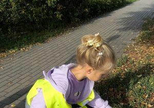 Dziecko zbiera odpady z terenu zielonego.