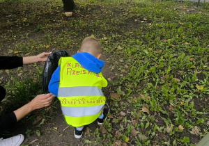 Dziecko zbiera odpady z terenu zielonego.