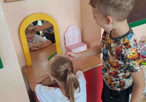 Dziewczynka i chłopiec bawią się w salon fryzjerski