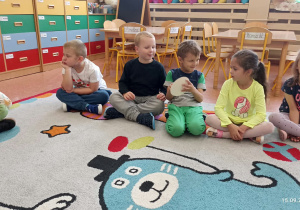 Dzieci siedzą w kole i bawią się w zabawy z kołem