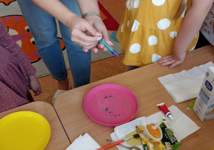 Pani pokazuje, jak należy wykonać eksperyment