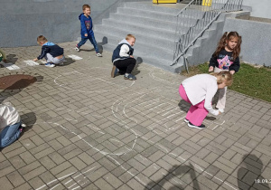 Dzieci rysują kredą miasteczko na chodniku