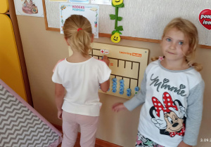 Dwie dziewczynki bawią się tablicą manipulacyjną