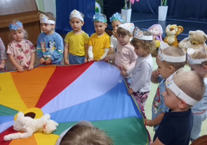 Dzieci stoją w kręgu i trzymają chustę animacyjną.