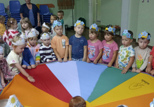 Dzieci w opaskach na głowie bawią się chustą animacyjną.