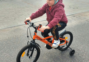 Chłopiec jedzie na rowerku, prawidłowo wyposażony w kask