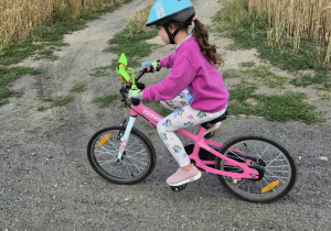 Dziewczynka jedzie na rowerku, prawidłowo wyposażona w kask
