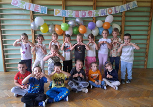 Pamiątkowa grupowa fotografia na tle napisu i balonów