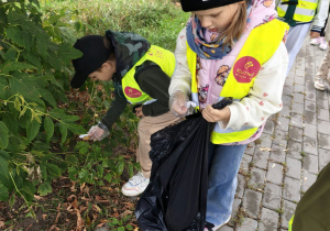 Dzieci zbierają śmieci z pobliskich ulic i trawników