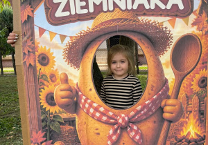 Dziecko pozuje w dekoracyjnej fotościance z motywem pieczonego ziemniaka