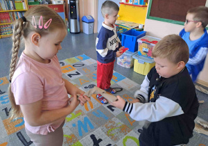 Dzieci tworzą drzewo jabłoni z szarego papieru