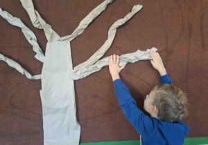 Dzieci tworzą drzewo jabłoni z szarego papieru