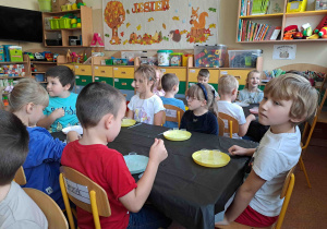 Dzieci przy stoliczkach za pomocą pipetek mieszają płyny