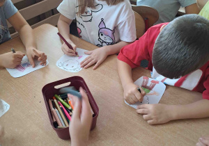 Dzieci wykonują papierowe sylwety postaci