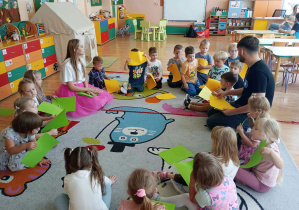 Animatorzy pokazują zabawę z papierem kolorowym przedszkolakom.