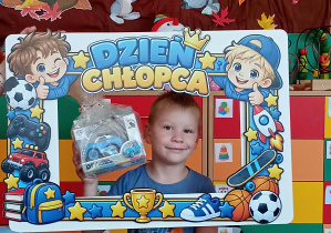 Chłopiec w niebieskiej koszulce trzyma upominek w ręku.