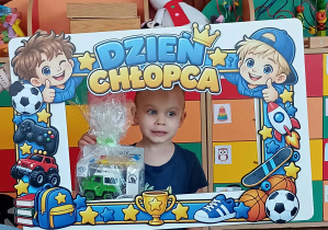 Chłopiec stoi w ramce i pozuje do zdjęcia.