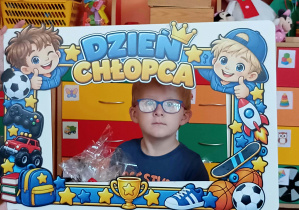 Chłopiec w okularach robi sobie zdjęcie.