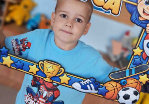 Chłopiec pozuje do zdjęcia w okolicznościowej ramce