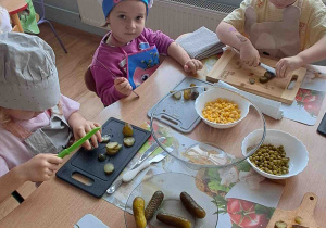 Dzieci kroją na deseczkach warzywa na sałatki