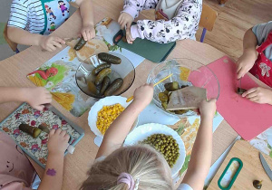 Dzieci kroją na deseczkach warzywa na sałatki