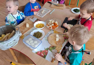 Dzieci kroją na deseczkach warzywa na sałatki