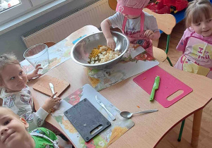 Dzieci kroją na deseczkach warzywa na sałatki